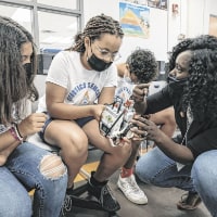 Shannell Carroll, from left, and Miyanna Haywood talk with instructor Ebun Okuleye-Ashwatch during a robotics competition at a camp held by Purdue Polytechnic Columbus. (The Republic photo/Mike Wolanin)