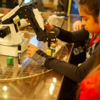 Elementary school students learn to execute tasks with a robotic arm much like those found in advanced manufacturing facilities.